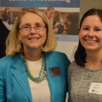An alumna and a faculty member smile for a photo together at the Academic Major Fair.
